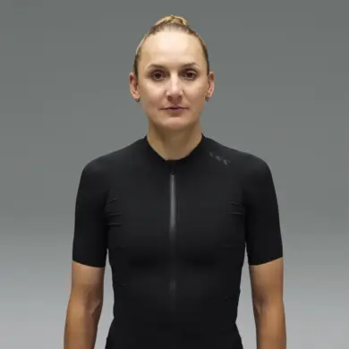 Frau in einem schwarzen Canyon CFR Damen-Rennradtrikot mit kurzem Reißverschluss und dezentem Logo