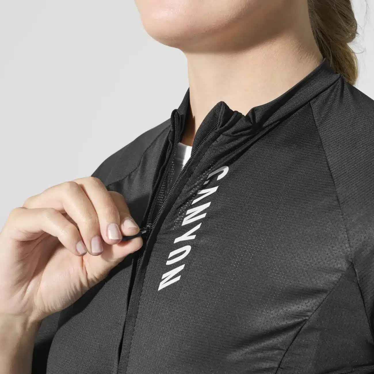 Nahaufnahme des Canyon CORE Women's Cycling Jersey in Schwarz, mit dem Fokus auf den Reißverschluss und das vertikal angebrachte weiße