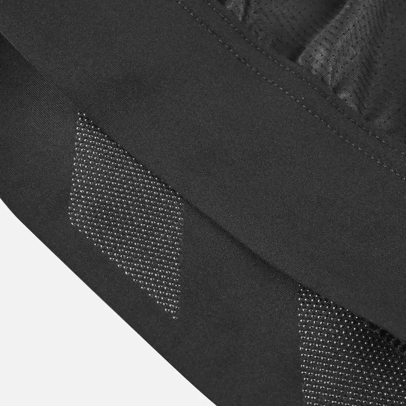 Nahaufnahme des schwarzen Canyon CORE Women’s Cycling Jersey mit Fokus auf den Silikon-Gripper und perforierte Mesh-Einsätze am Saum zur Verbesserung des Sitzes und der Belüftung.