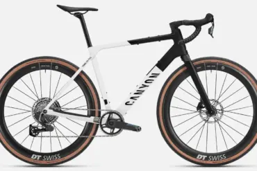 Seitenansicht eines Canyon Grail CF SLX 8 AXS Gravelbikes in den Farben Weiß und Schwarz mit braunen Reifen und DT Swiss Carbonlaufrädern.