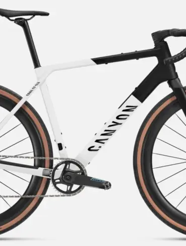 Seitenansicht eines Canyon Grail CF SLX 8 AXS Gravelbikes in den Farben Weiß und Schwarz mit braunen Reifen und DT Swiss Carbonlaufrädern.