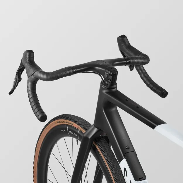 Detailaufnahme des Cockpits und Vorderrads eines schwarzen Canyon Grail CF SLX 8 AXS Gravelbikes mit Carbonrahmen und braunen Reifen.