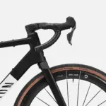 Detailansicht des Lenkers und des Vorderrads eines schwarzen Canyon Grail CF SLX 8 Di2 Gravelbikes mit braunen Reifen.
