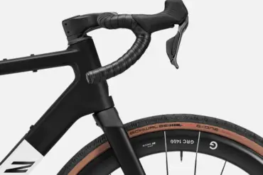 Detailansicht des Lenkers und des Vorderrads eines schwarzen Canyon Grail CF SLX 8 Di2 Gravelbikes mit braunen Reifen.