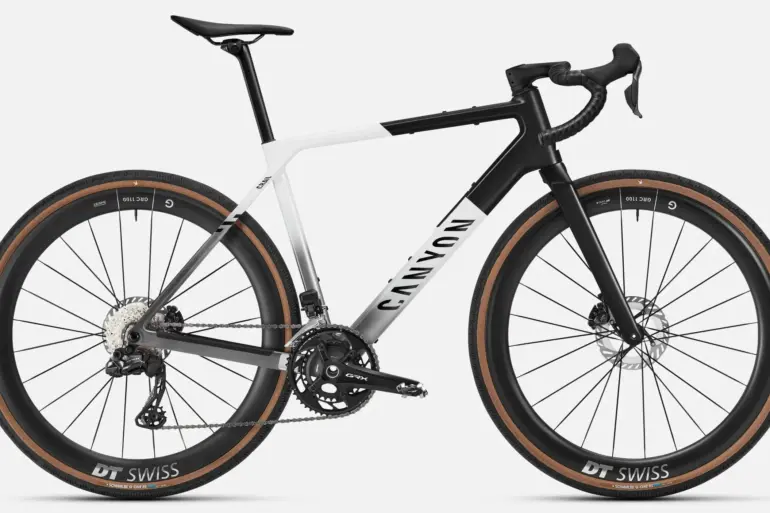 Seitenansicht eines Canyon Grail CFR Di2 Gravelbikes in weiß und schwarz mit braunen Reifen.