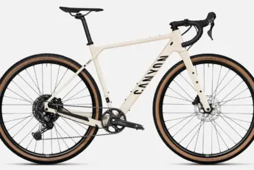 Ein sandfarbenes Canyon Grizl 5 Gravelbike von vorne, mit Fokus auf den Rahmen, die Gabel, die breiten Reifen und die Shimano Cues Schaltung.