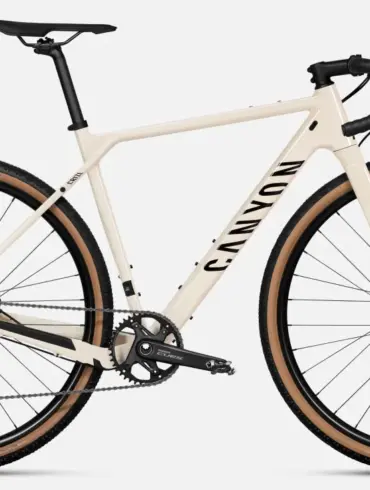 Ein sandfarbenes Canyon Grizl 5 Gravelbike von vorne, mit Fokus auf den Rahmen, die Gabel, die breiten Reifen und die Shimano Cues Schaltung.