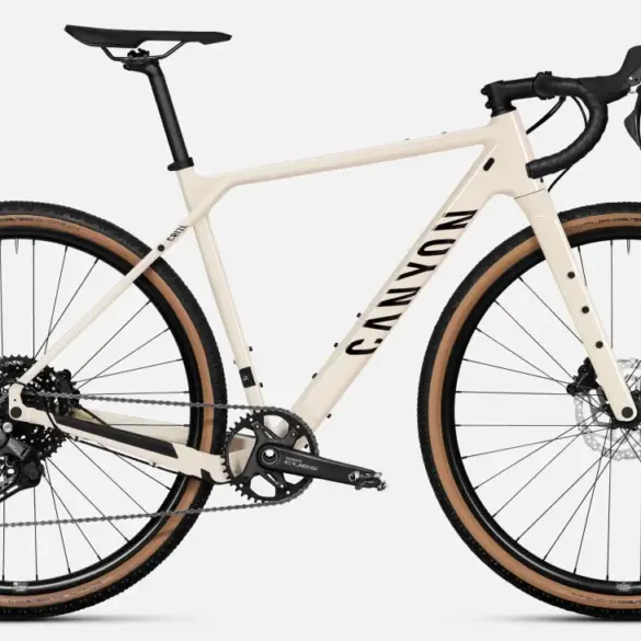 Ein sandfarbenes Canyon Grizl 5 Gravelbike von vorne, mit Fokus auf den Rahmen, die Gabel, die breiten Reifen und die Shimano Cues Schaltung.