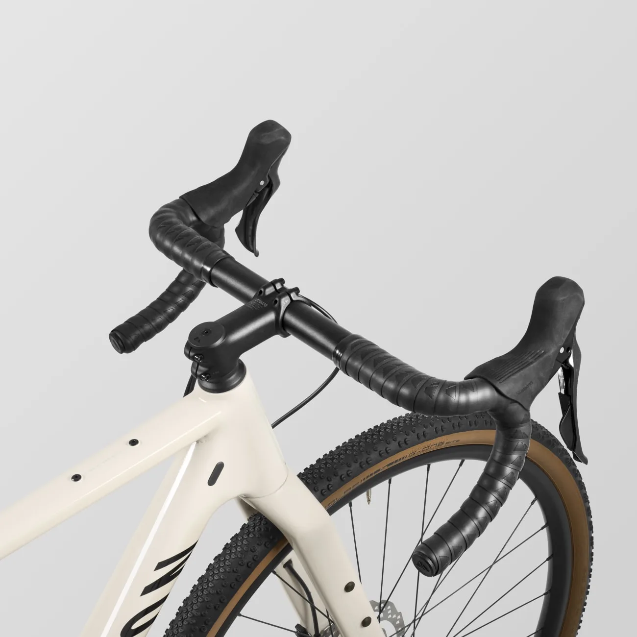 Nahaufnahme eines cremefarbenen Canyon Grizl 5 Gravelbikes mit schwarzem Lenker, Bremshebeln und Vorderreifen.