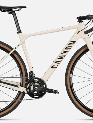 Seitenansicht eines Canyon Grizl 7 Gravelbikes in heller Sandfarbe mit schwarzen Akzenten, ausgestattet mit Schwalbe G-One Reifen und DT Swiss Laufrädern.
