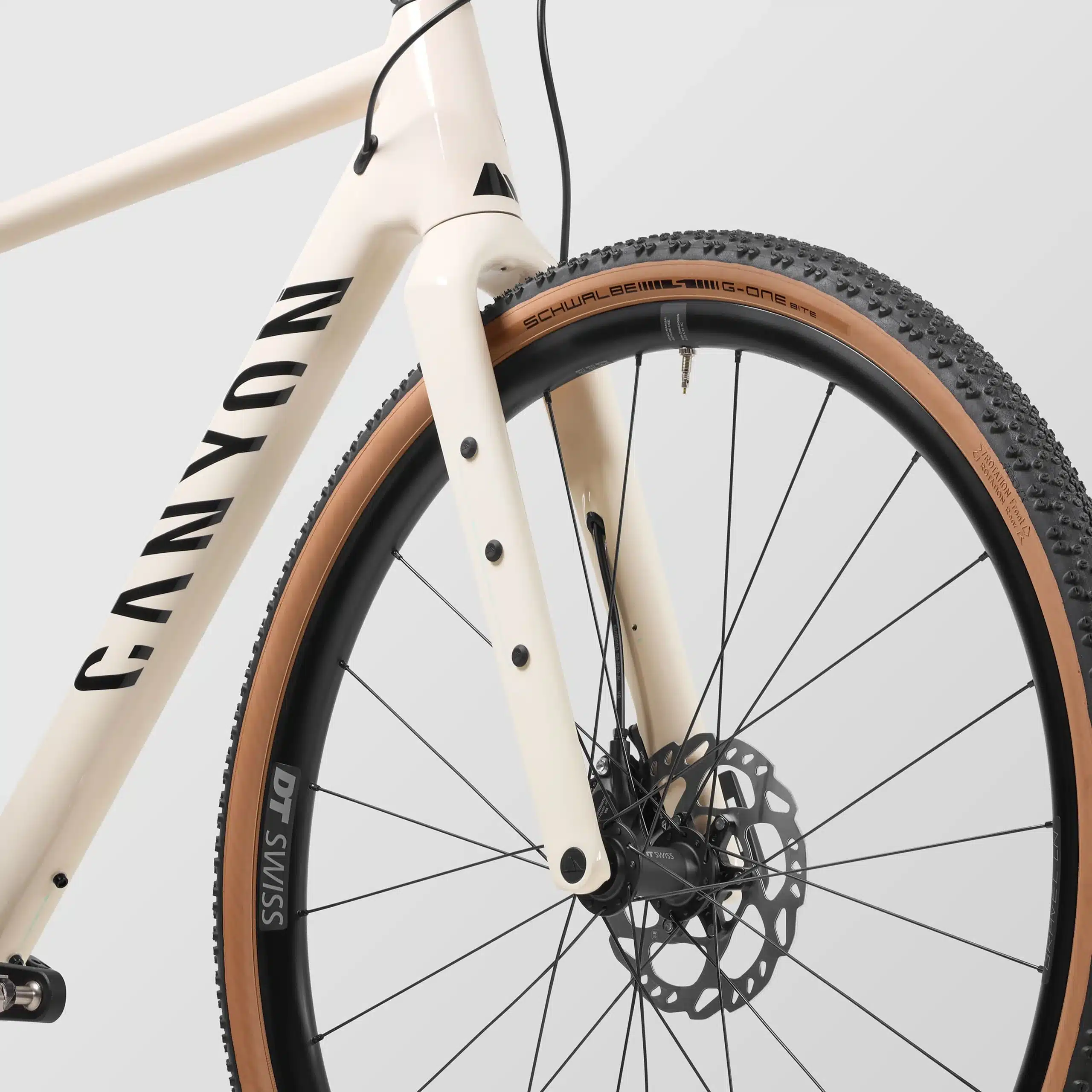 Vorderansicht eines cremefarbenen Canyon Grizl 7 Gravelbikes mit breiten Schwalbe G-One Bite Reifen und schwarzen DT Swiss Felgen.