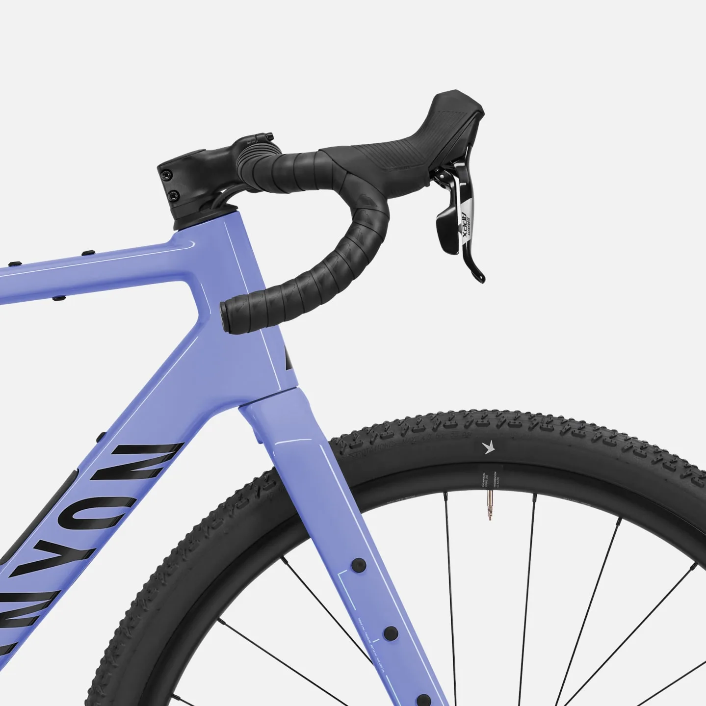 Nahaufnahme des Canyon Grizl CF 6 Gravelbikes mit Fokus auf den Lenker, die Gabel und einen Teil des Rahmens. Das Fahrrad ist in einem hellen Lavendelton gehalten.