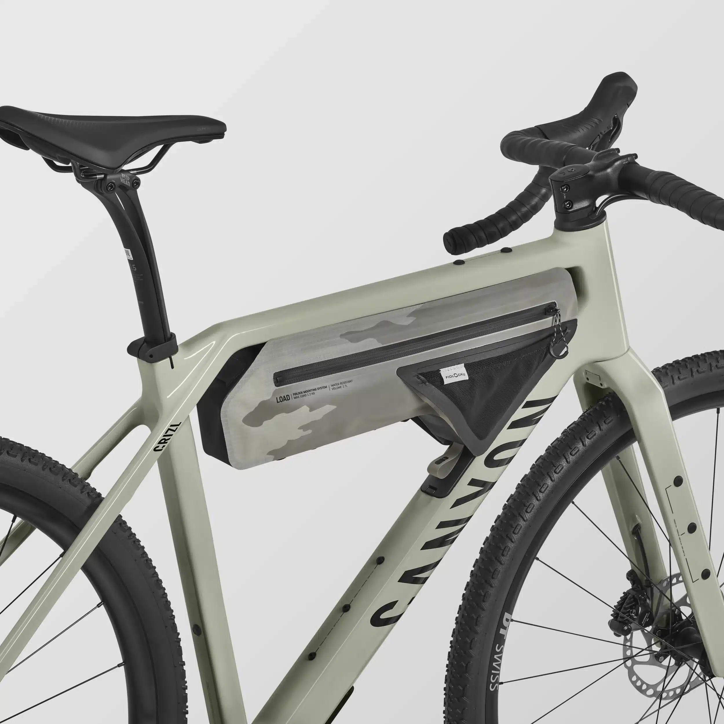 Seitenansicht eines Canyon Grizl CF 7 Gravelbikes in heller Farbe, ausgestattet mit einer grauen Tarnmuster-Rahmentasche und schwarzen Reifen.