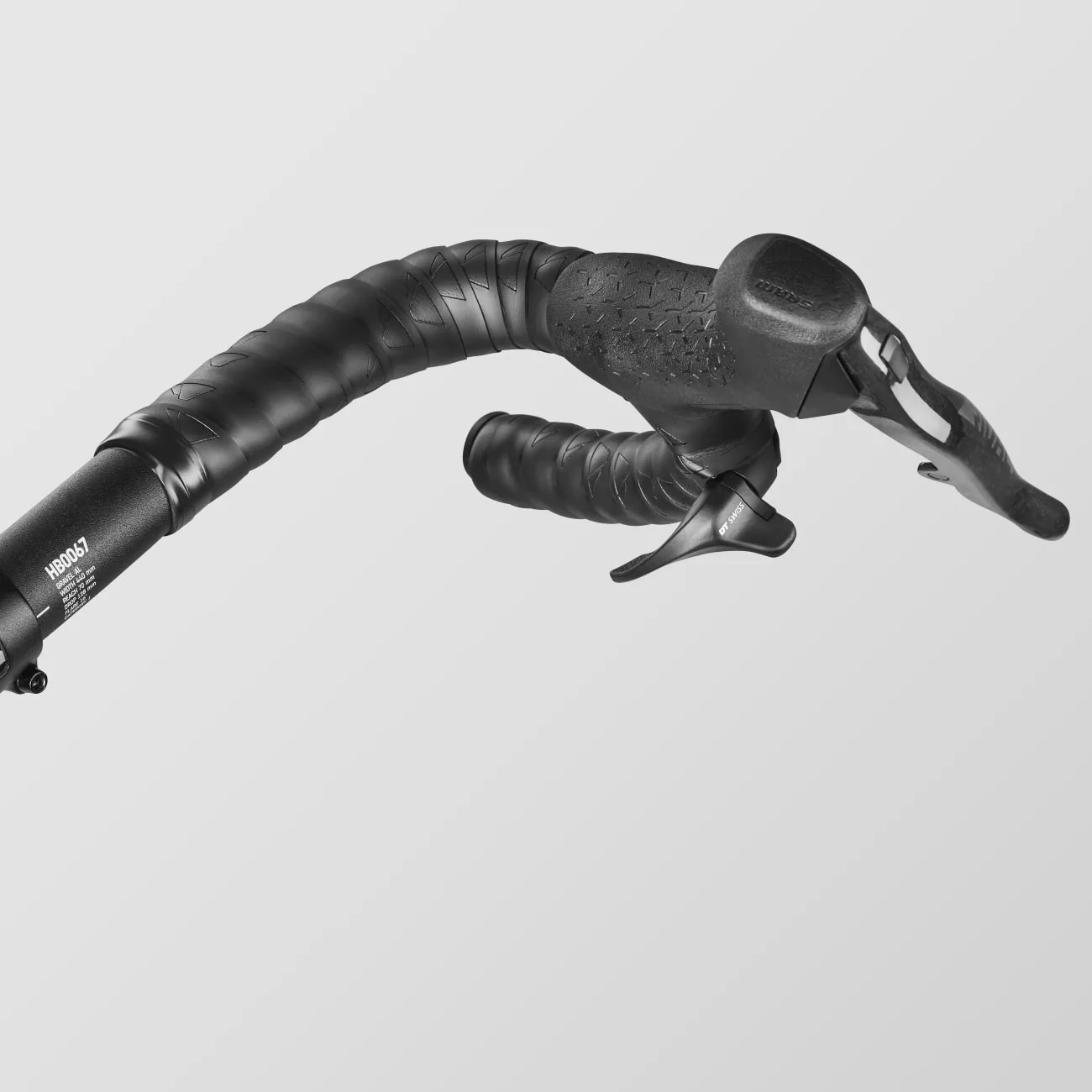 Schwarz lackierter Fahrradlenker mit schwarzem Lenkerband und einem silbernen Schalthebel, aufgenommen aus der Nähe.