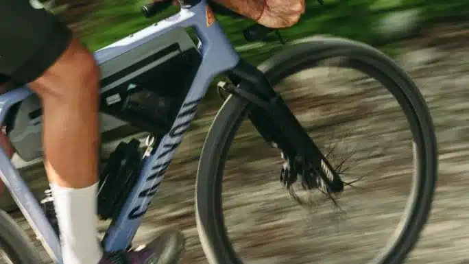 Nahaufnahme des vorderen Rahmens und des Vorderrads eines Canyon Grizl CF 9 ESC w/ RIFT Gravelbikes, das auf einer Schotterpiste fährt.