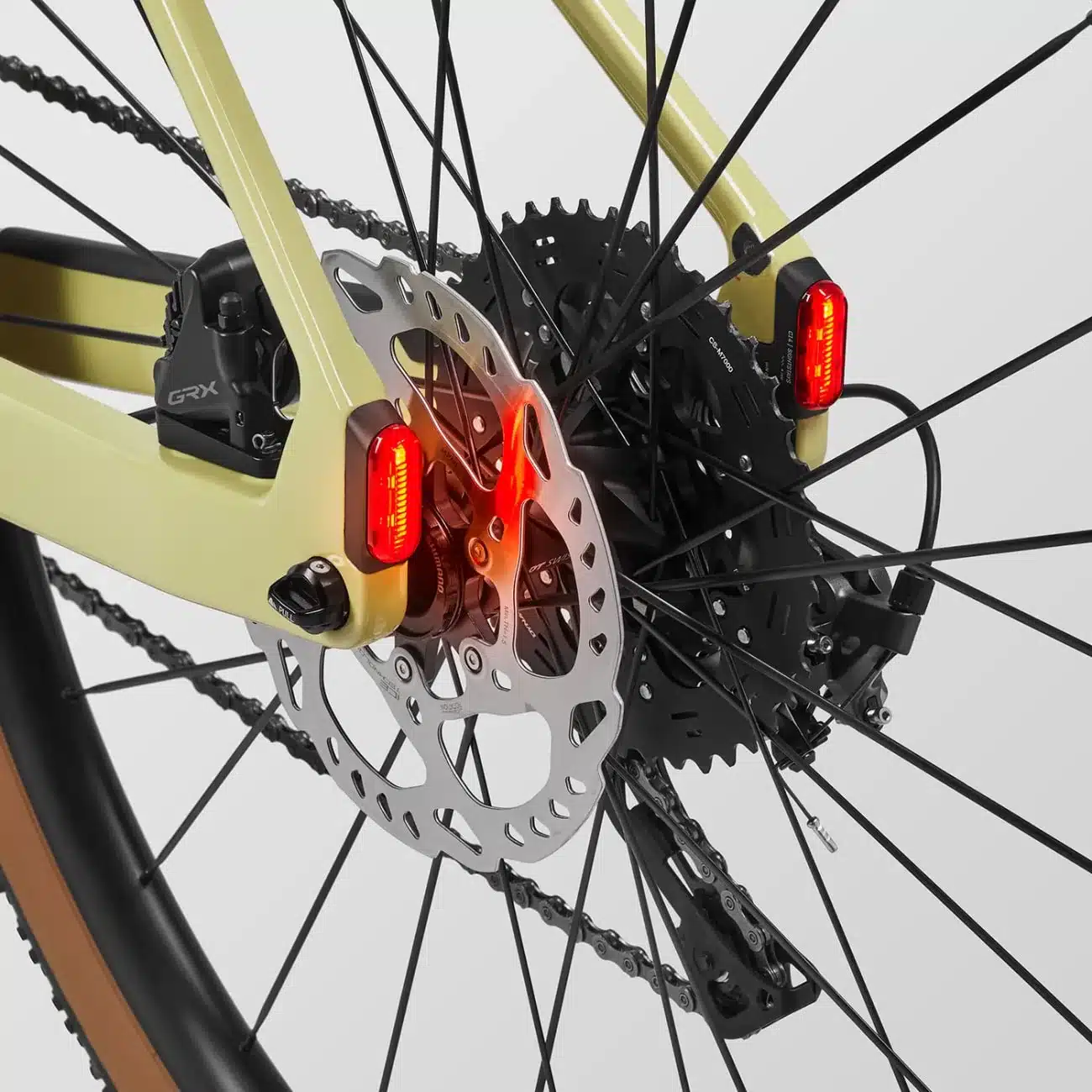 Detailaufnahme des Hinterrads eines Canyon Grizl:ONfly CF 7 E-Gravelbikes, zeigt die Kassette, das Schaltwerk, die Scheibenbremse und die integrierten roten Rückleuchten.