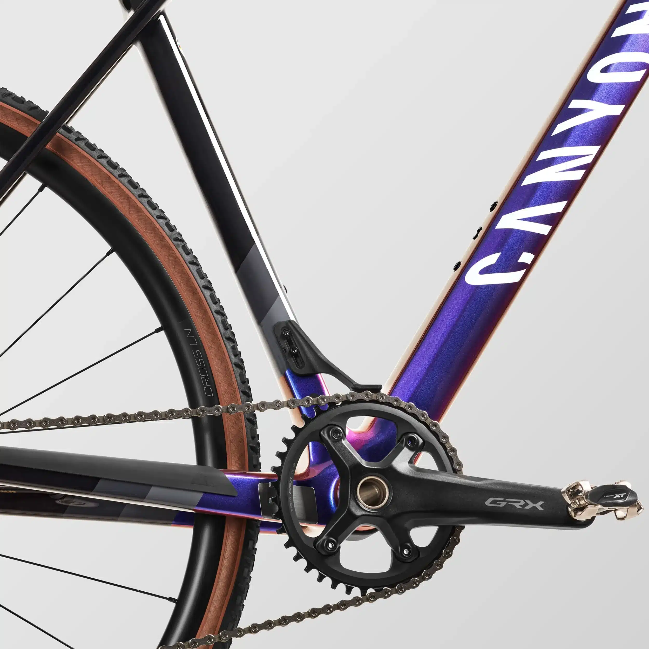 Detailansicht des Canyon Inflite CF SL 5 Fahrrads, Fokus auf Kurbelgarnitur, Kette und den lila-goldenen Rahmen.