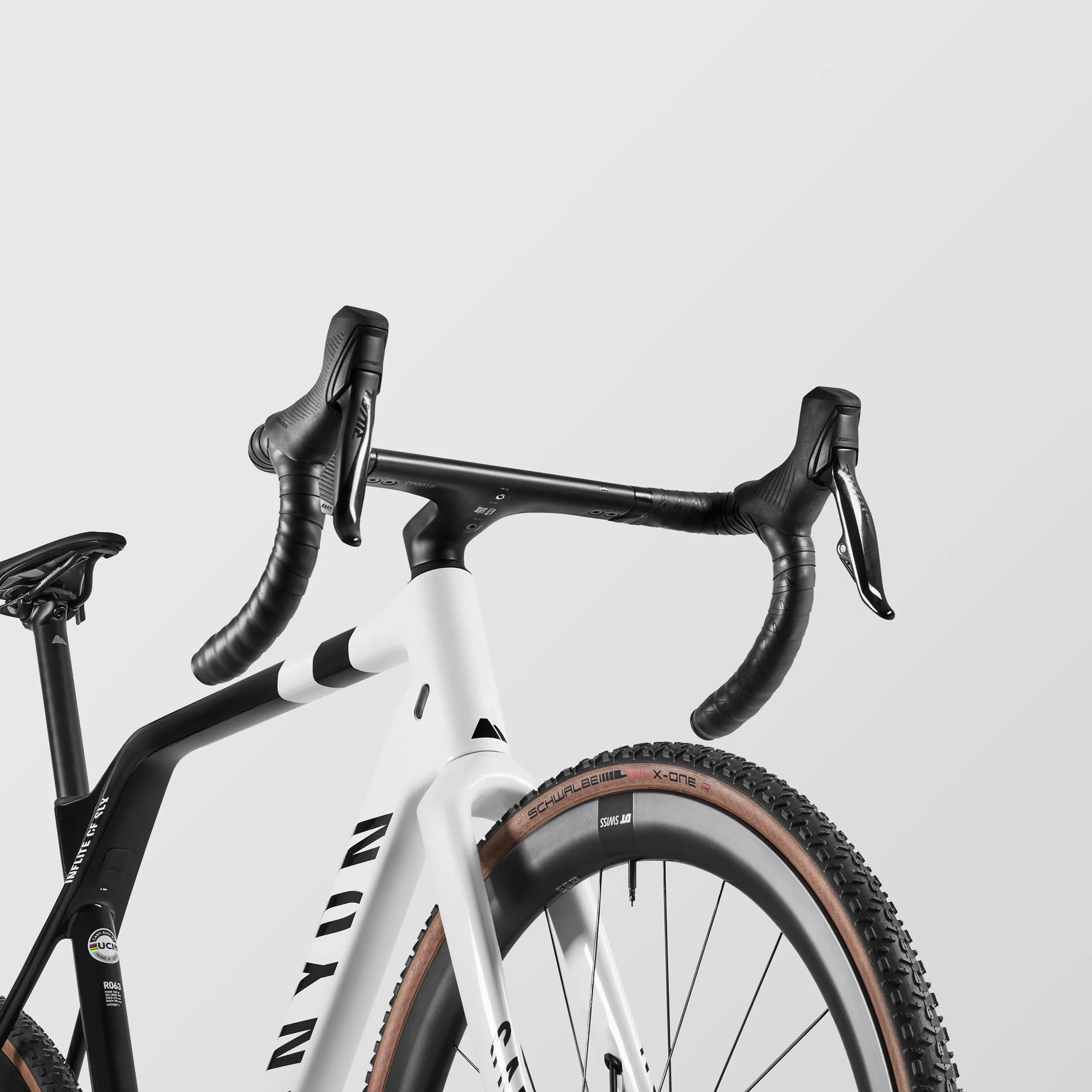 Vorderansicht eines Canyon Inflite CF SLX 7 Cyclocross-Rads mit weißem Rahmen, schwarzen Lenkergriffbändern und einem Vorderrad mit Schwalbe X-One Reifen.