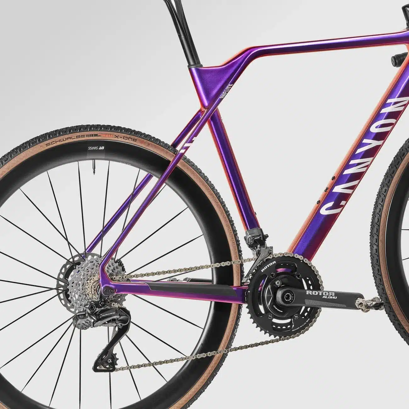 Detailansicht eines Canyon Inflite CFR Cyclocross-Rads mit lila-orange Farbverlauf, Schwalbe X-One Reifen und Shimano Dura Ace Schaltung.