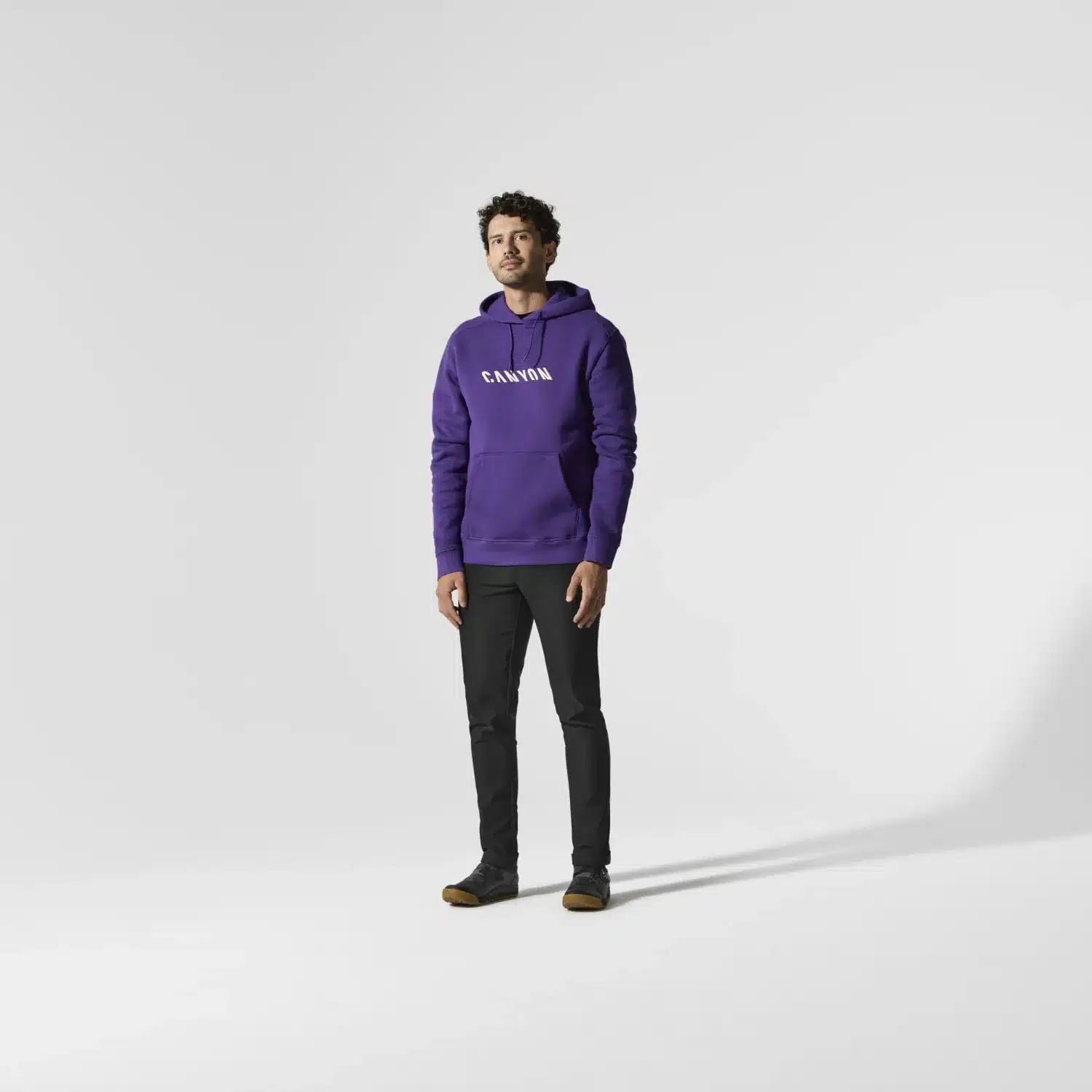 Ein Mann trägt einen lilafarbenen Hoodie mit dem Schriftzug