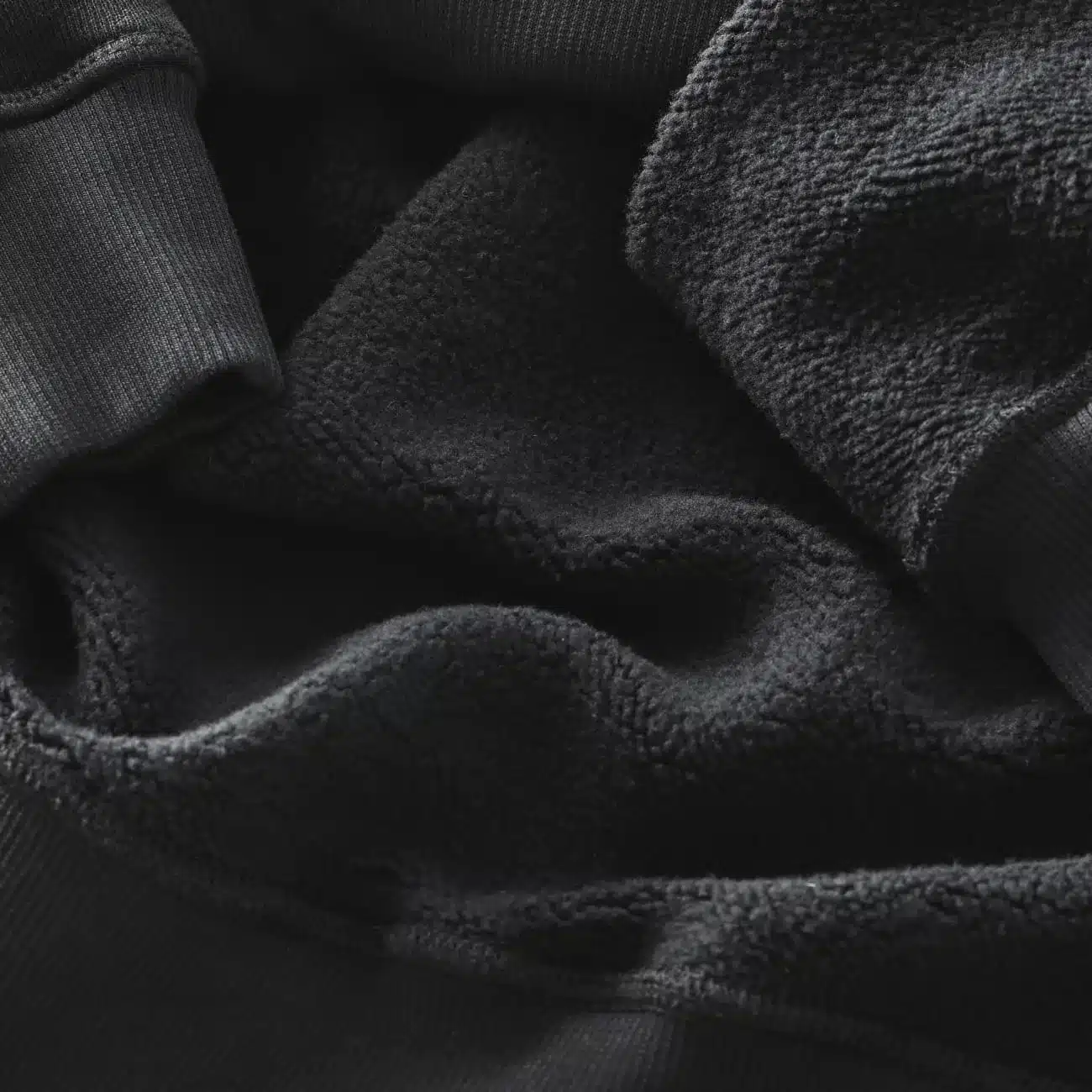 Nahaufnahme des weichen, flauschigen Innenfutters eines schwarzen Canyon Men's Hoodie, das für Komfort und Wärme sorgt. Man erkennt die Textur des Materials und die gerippten Bündchen.