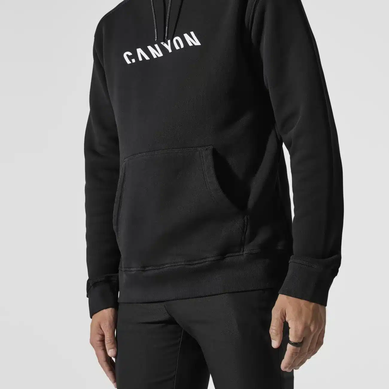 Nahaufnahme eines Mannes, der einen schwarzen Canyon Hoodie mit weißem