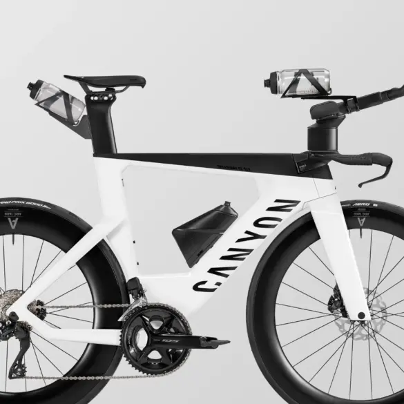 Seitenansicht eines weißen Canyon Speedmax CF SLX 7 Di2 Triathlonrads mit integrierten Trinkflaschen und Aero-Aufsätzen.