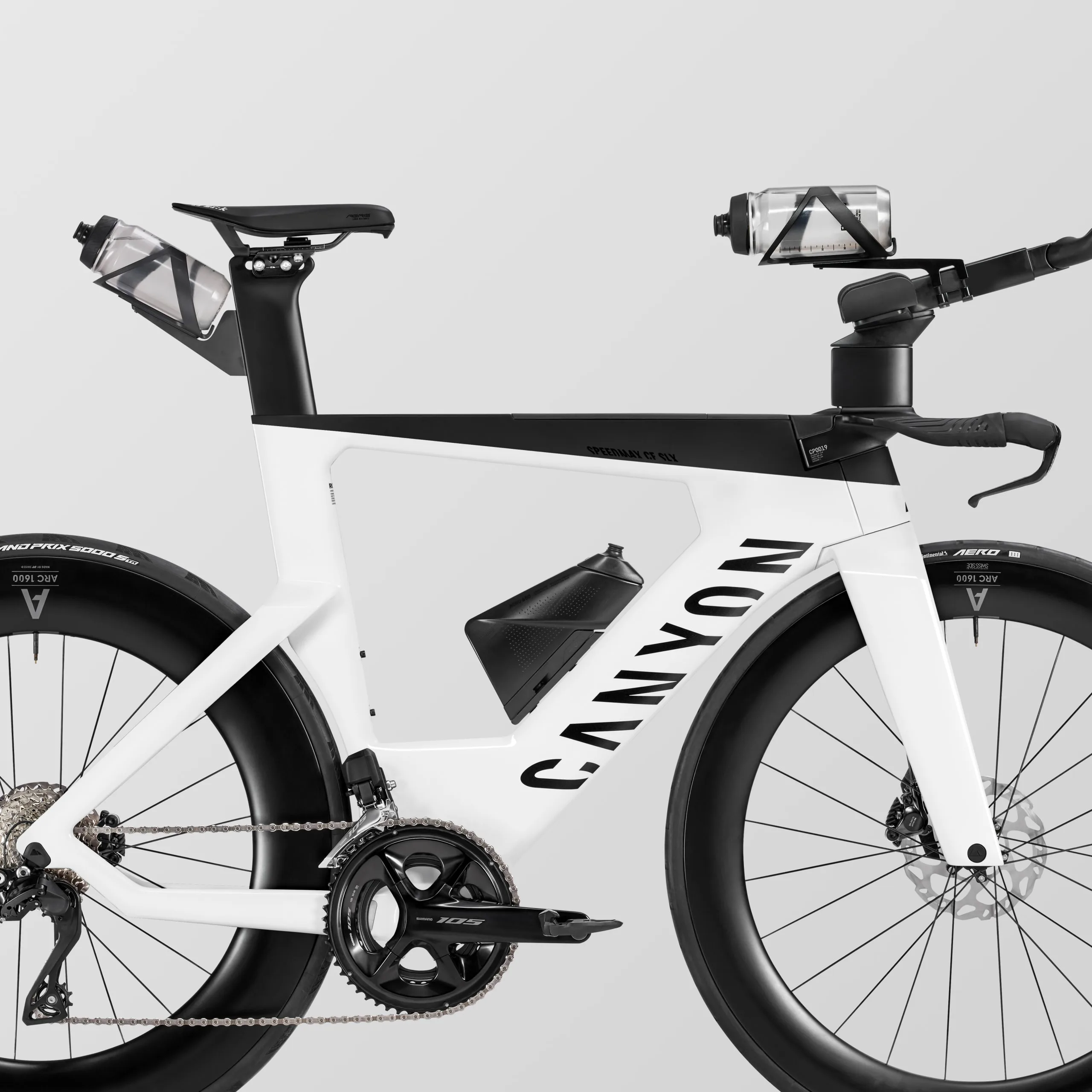 Seitenansicht eines weißen Canyon Speedmax CF SLX 7 Di2 Triathlonrads mit integrierten Trinkflaschen und Aero-Aufsätzen.
