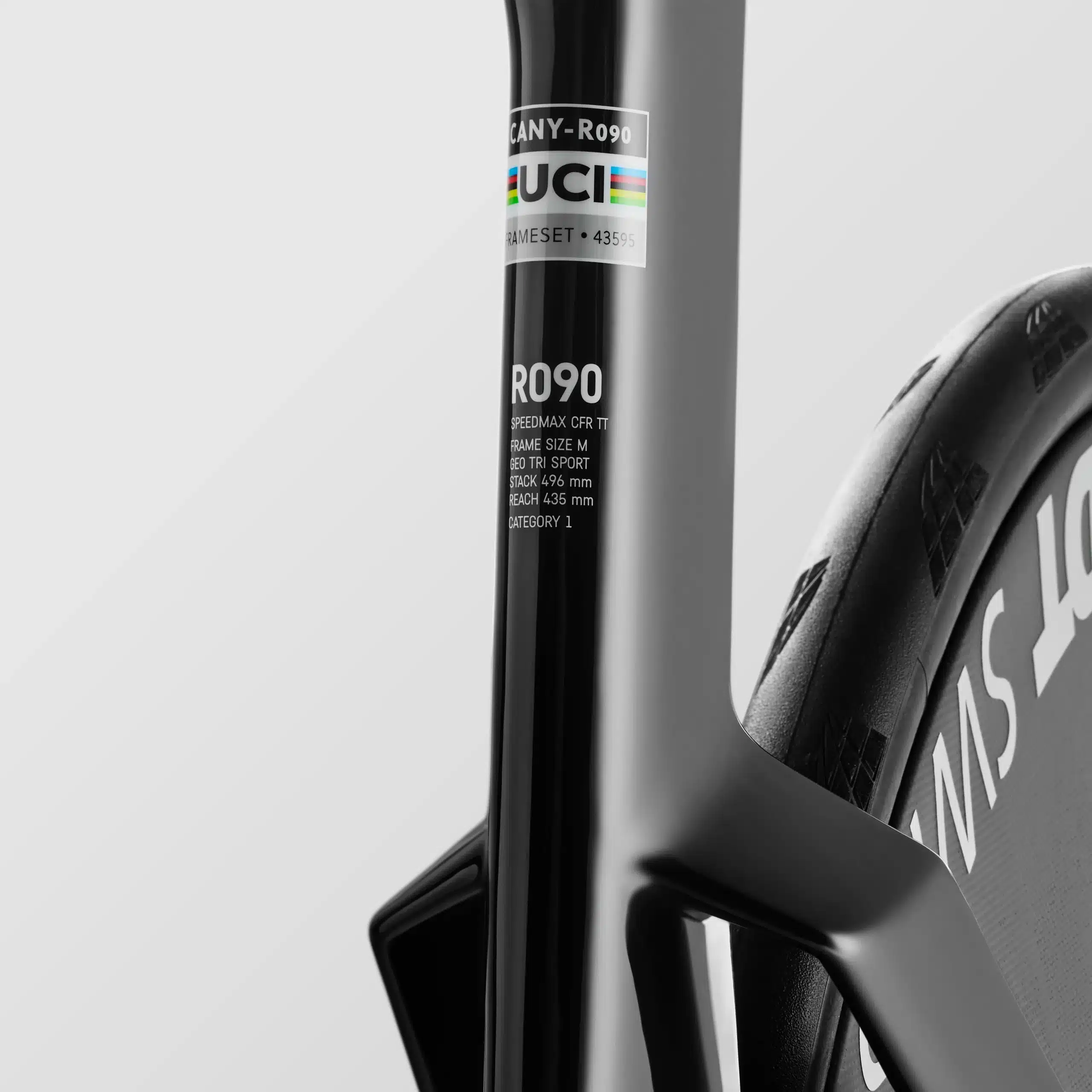 Detailansicht eines schwarzen Canyon Speedmax CFR TT Zeitfahrradrahmens mit sichtbarem UCI-Aufkleber und dem Schriftzug 'R090' sowie einem Teil des DT Swiss ARC 1100 Dicut Laufrads.