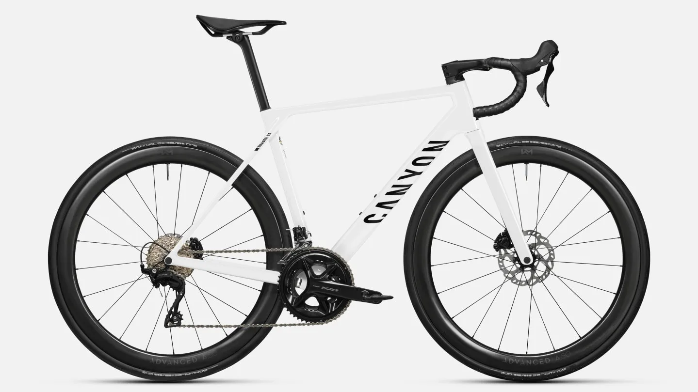Seitenansicht eines weißen Canyon Ultimate CF 7 A.50 Rennrads mit schwarzen Carbonlaufrädern und Shimano 105 Komponenten.