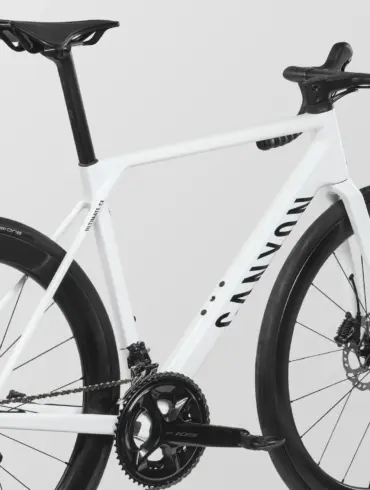Detailansicht eines weißen Canyon Ultimate CF 7 A.50 Rennrads, Fokus auf den Carbonrahmen, die Kurbelgarnitur und das Hinterrad.