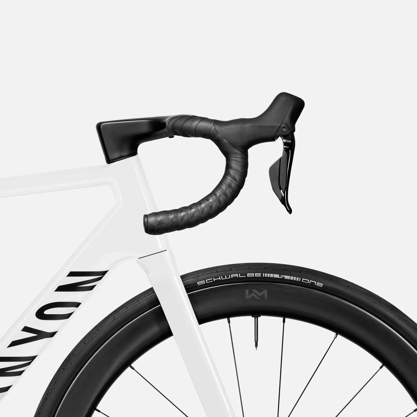 Detailaufnahme eines weißen Canyon Rennrads mit Fokus auf das integrierte Cockpit, den Lenker mit schwarzem Lenkerband und den Shimano 105 Di2 Schalt-/Bremshebel. Daneben ist das Vorderrad mit einem Schwalbe Reifen und einer schwarzen Felge zu sehen.