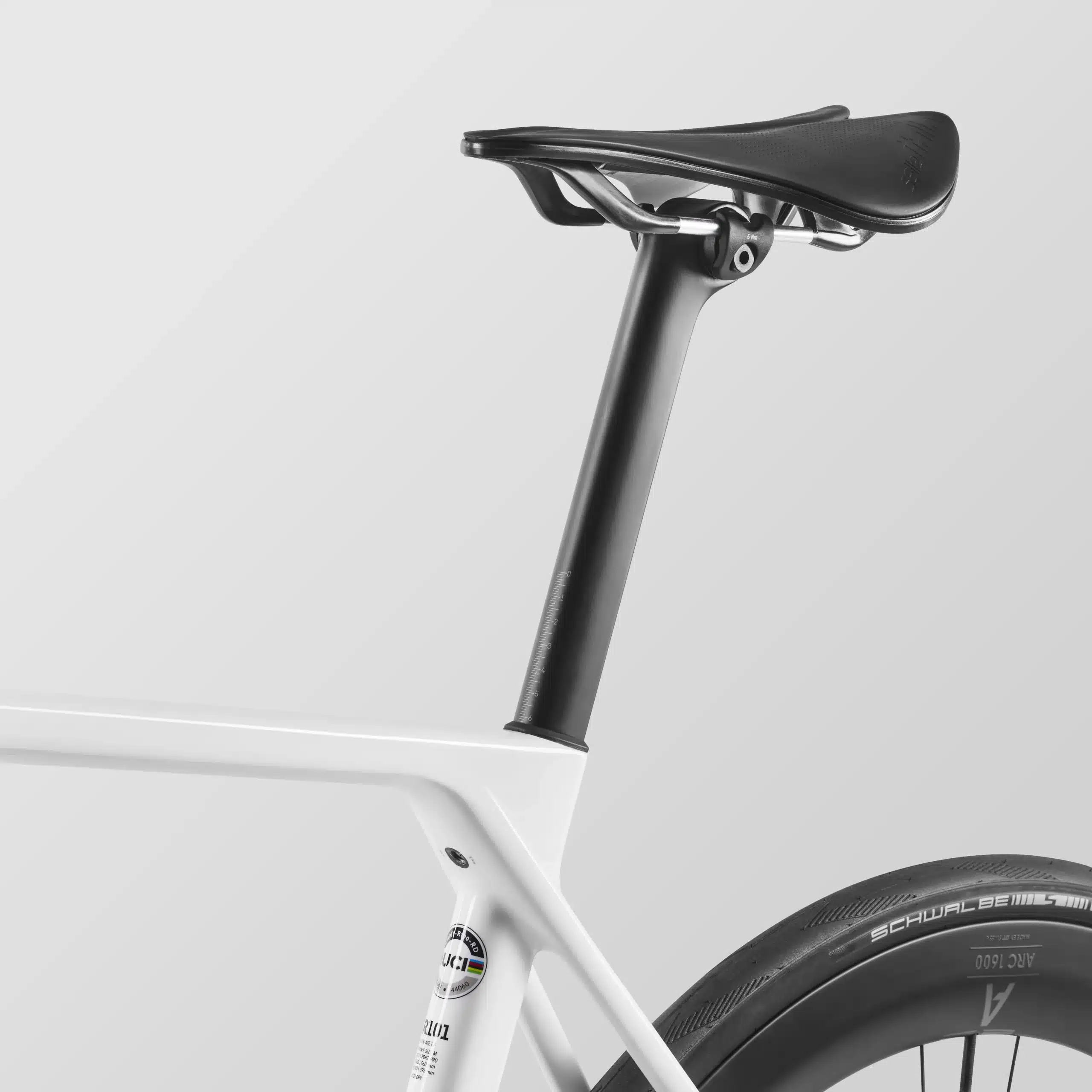Detailaufnahme des Sitzbereichs eines weißen Canyon Ultimate CF 7 Di2 Aero Rennrads mit schwarzer Sattelstütze, schwarzem Sattel und schwarzem Carbon-Laufrad.