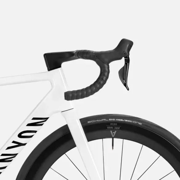 Nahaufnahme des weißen Canyon Ultimate CF 7 Di2 AERO Rennrads, Fokus auf Lenker, Vorbau und Vorderrad mit schwarzem Reifen und Felge.