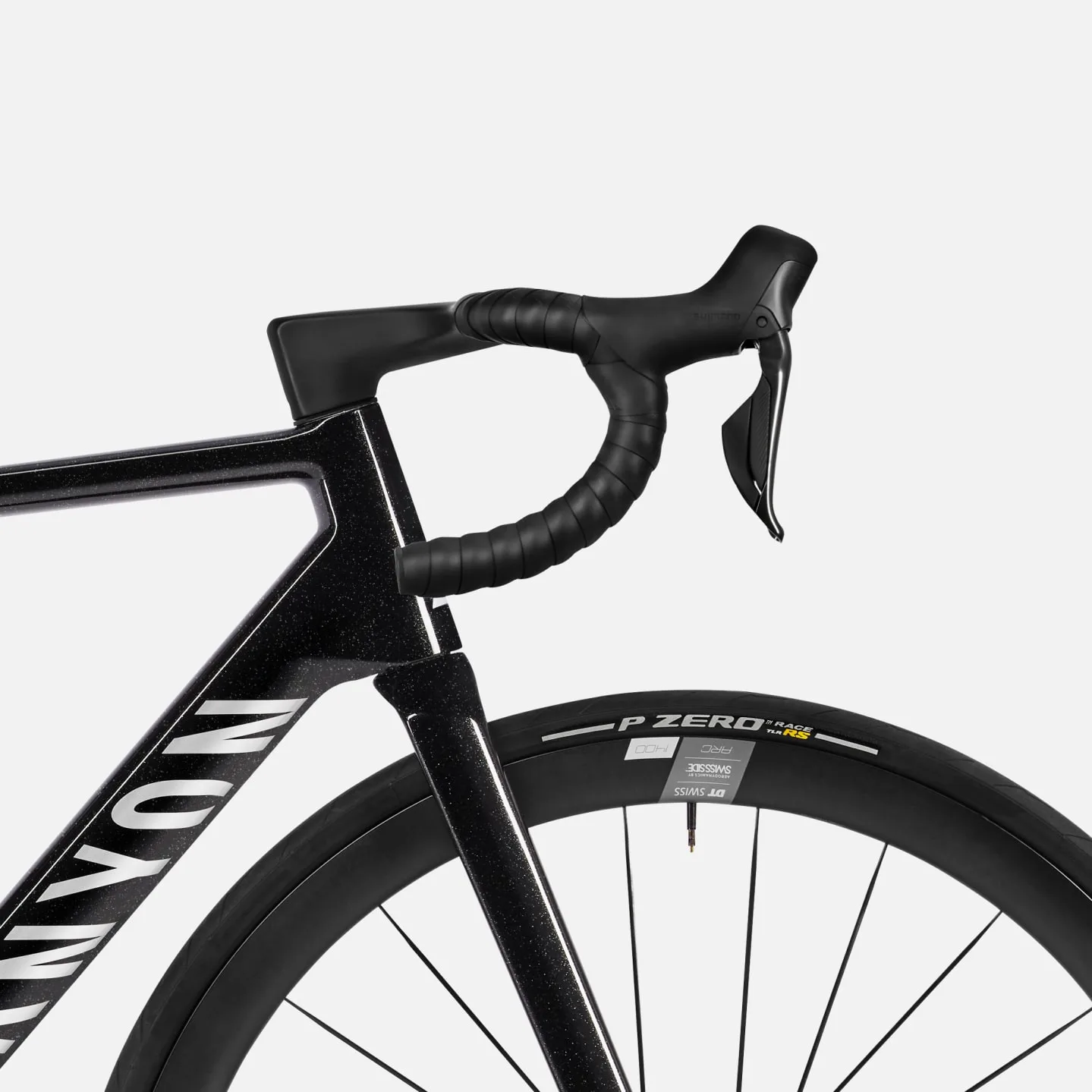 Nahaufnahme des schwarzen Canyon Ultimate CF SLX 8 Di2 Rennrads mit Fokus auf den integrierten Lenker, das Markenlogo auf dem Rahmen und das DT Swiss Laufrad mit Pirelli P Zero Race Reifen.