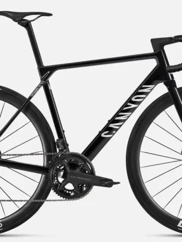 Seitenansicht eines schwarzen Canyon Ultimate CF SLX 8 Di2 Rennrads mit DT Swiss Carbon-Laufrädern und Shimano Ultegra Di2 Schaltung auf grauem Hintergrund.
