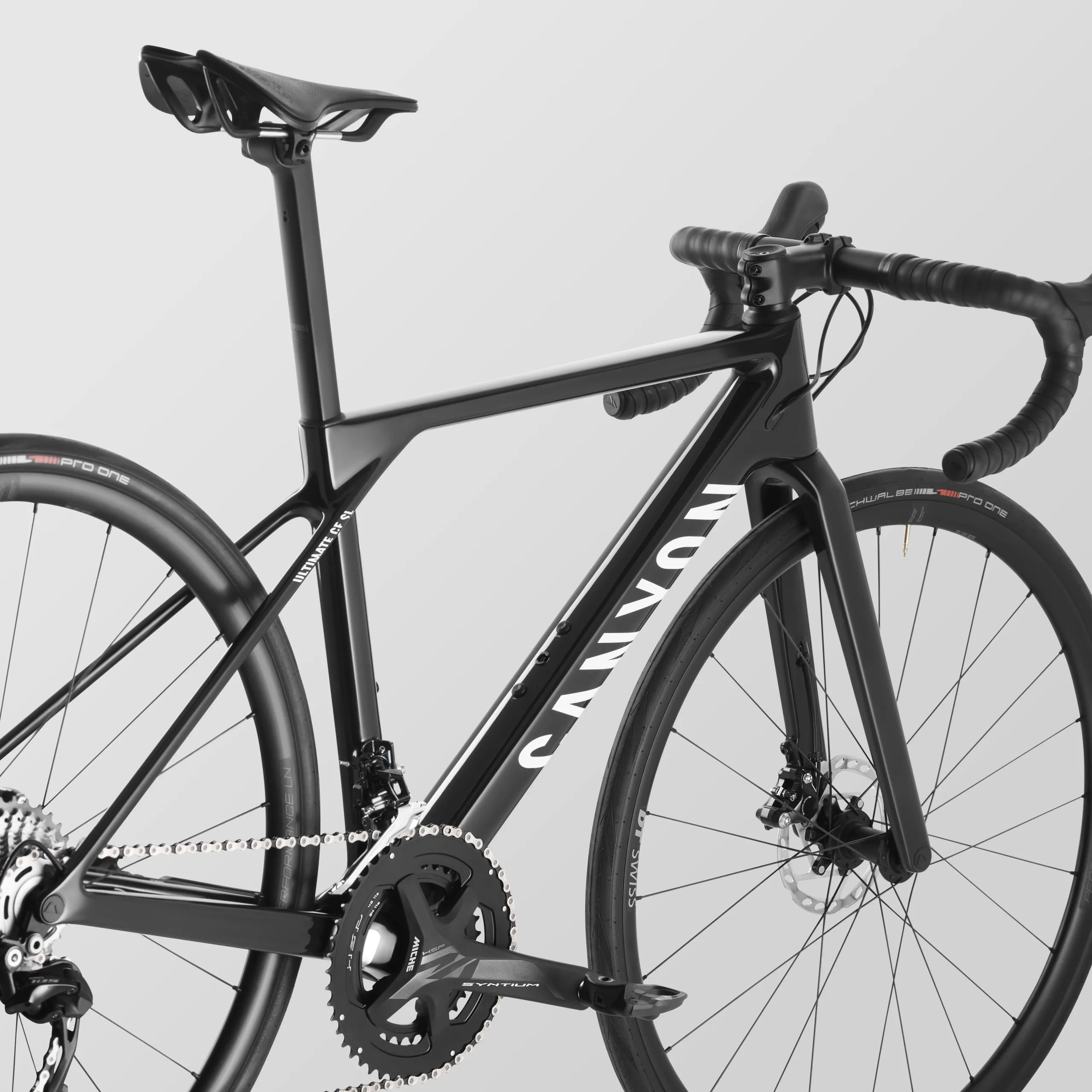 Ein schwarzes Canyon Ultimate CF Young Hero Rennrad, detailreich abgebildet mit Fokus auf den Rahmen, die Kurbelgarnitur und die Laufräder.