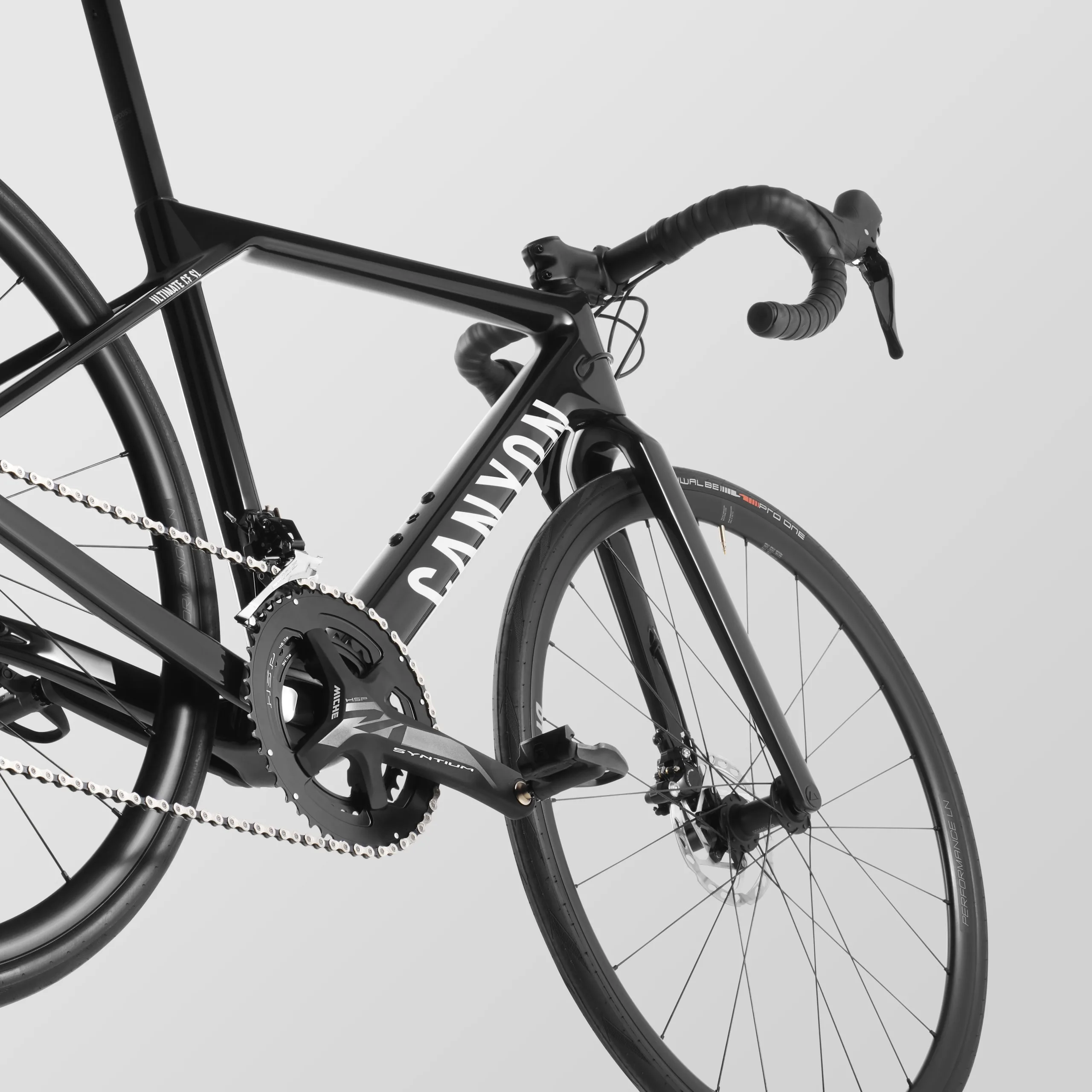 Schwarz lackiertes Canyon Ultimate CF Young Hero Rennrad mit Fokus auf den vorderen Rahmenbereich, die Kurbelgarnitur und das Vorderrad.