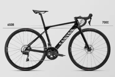 Seitenansicht eines schwarzen Canyon Ultimate CF Young Hero Rennrads mit der Kennzeichnung "650B" auf der linken Seite und "700C" auf der rechten Seite, was auf die unterschiedlichen Laufradgrößen hinweist.