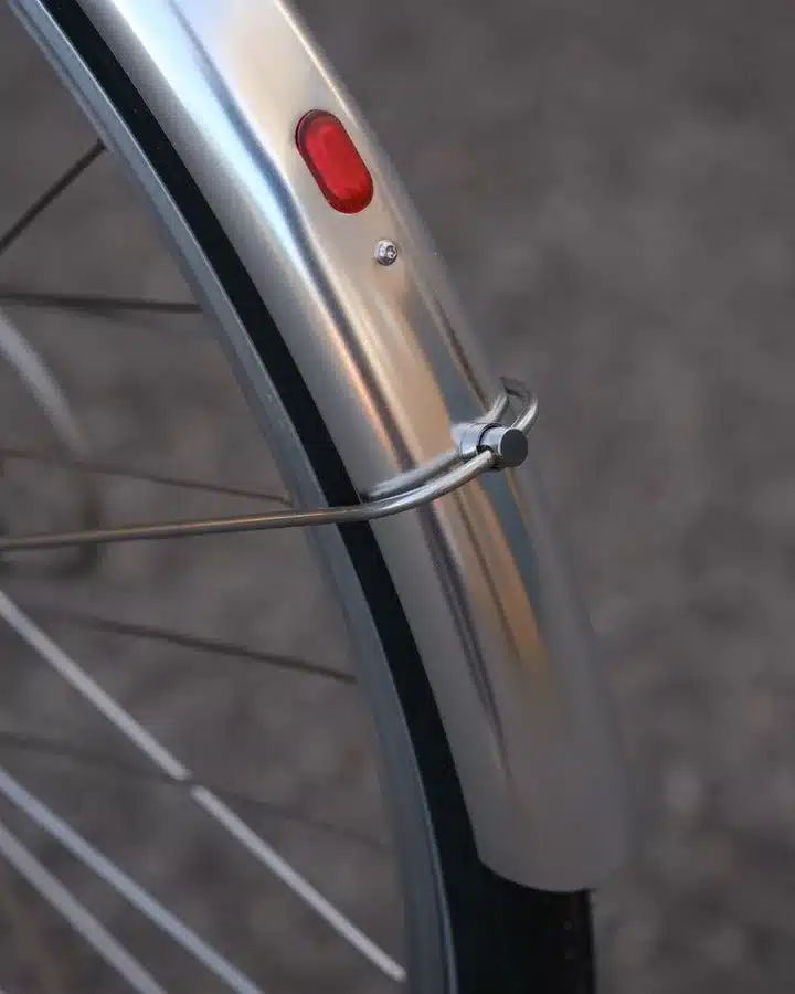 Nahaufnahme des silbernen Schutzblechs eines Capri Azur 4 Fahrrads mit montiertem roten Rücklicht, Fokus auf den Radbereich.