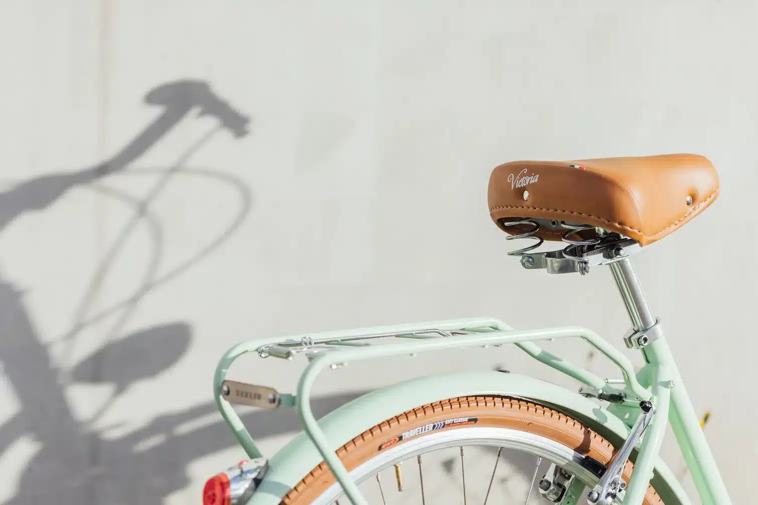 Nahaufnahme des hinteren Teils eines mintgrünen Capri Berlin Fahrrads, Fokus auf den braunen Ledersattel mit der Aufschrift