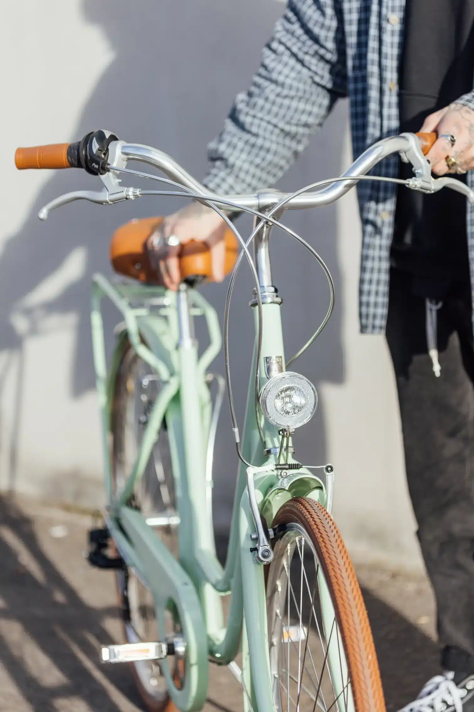 Mintgrünes Capri Berlin Fahrrad mit braunem Sattel, Chromlenker und silberner Lampe, nah aufgenommen.