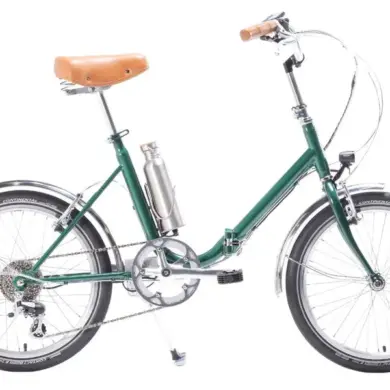 Ein dunkelgrünes Capri Electric Vita Faltrad mit braunem Sattel und braunen Griffen steht vor einem weißen Hintergrund. Es ist mit Schutzblechen, einer Flaschenhalterung mit silberner Trinkflasche und einer Lichtanlage ausgestattet.