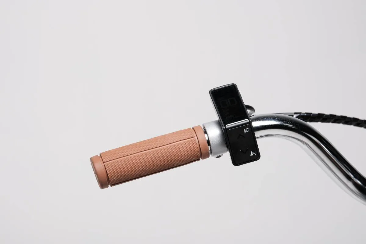 Nahaufnahme des rechten Lenkergriffs eines Capri Electric Vita E-Bikes mit schwarzem Display, Bedienelementen und einem braunen Griff.
