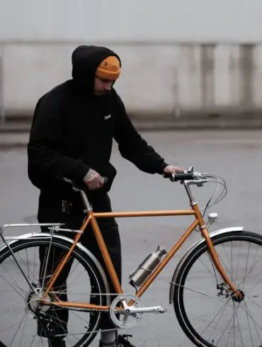 Orangefarbenes Capri Metz E-Bike mit einem Mann, der daneben steht.