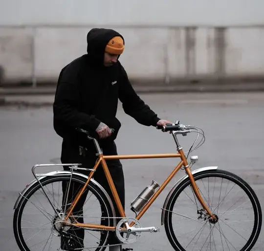 Orangefarbenes Capri Metz E-Bike mit einem Mann, der daneben steht.