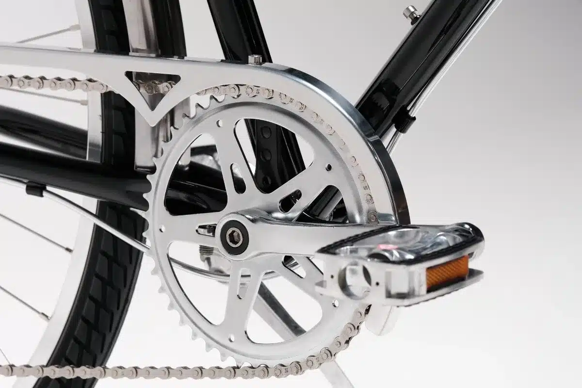 Nahansicht der silbernen Kurbelgarnitur mit Kette eines schwarzen Fahrrads, Fokus auf das Fahrrad-Detail.