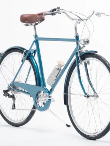 Blaues Capri Vienna Electric E-Bike mit braunem Ledersattel und silberner Wasserflasche, ausgestellt vor weißem Hintergrund.