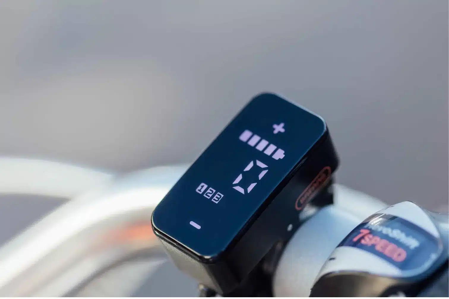 Digitales Display eines E-Bikes zeigt Akkuladung und Unterstützungsstufe an, daneben befindet sich ein Schalthebel für 7 Gänge.