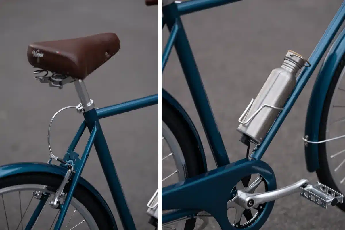 Detailansicht eines dunkelblauen Capri Vienna Electric E-Bikes, fokussiert auf den braunen Ledersattel mit silberner Federung und die Seitenansicht des Unterrohrs mit einem montierten silbernen Trinkflaschenhalter.